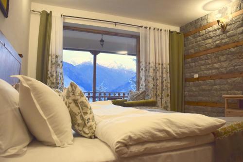 a bedroom with a large window with a mountain view at Kudrat - A Boutique Homestay- Tirthan Valley in Banjār