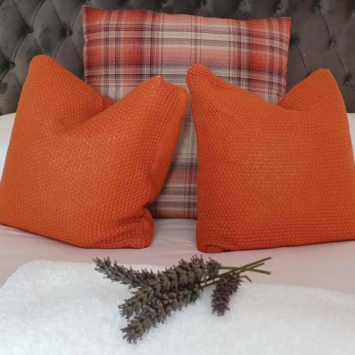 two orange pillows on a bed with a sprig of thyme at The Kings Arms - Fleggburgh in Burgh Saint Margaret