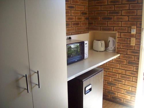 eine Küche mit einer Theke mit einem TV und einer Ziegelwand in der Unterkunft Cobar Town & Country Motor Inn in Cobar