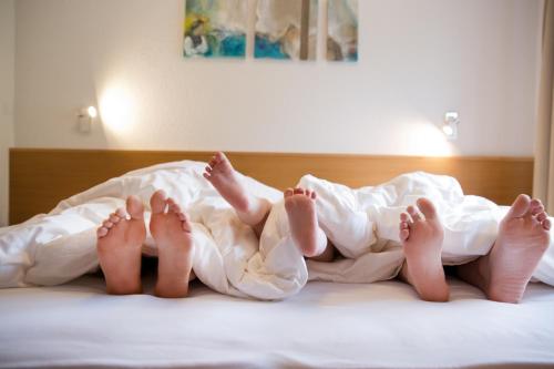 two people laying on a bed under a blanket at Appartements Berg 170 in Damuls