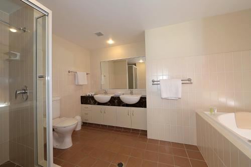 a bathroom with two sinks and a toilet and a mirror at Pacific Reef by Kacys in Bargara