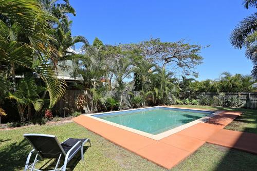 a swimming pool in a yard with two chairs at Pacific Reef by Kacys in Bargara