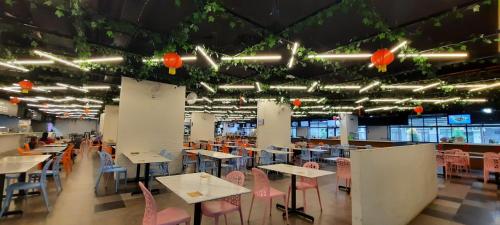 a dining room with tables and chairs and lights at Arena SOHO at Kozi Square Kuching in Kuching