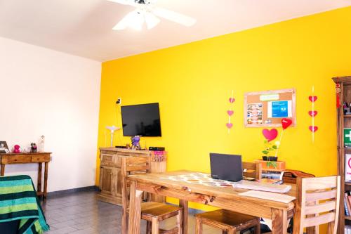 ein Esszimmer mit einem Tisch und einer gelben Wand in der Unterkunft SIGRUM Hostel in San Rafael