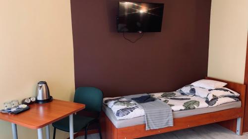 a room with a bed and a desk and a table at Bianco - pokoje noclegowe in Częstochowa