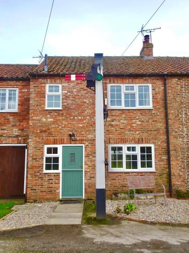 a brick house with a green door and a pole at Signal Cottage at The Red House Estate in York