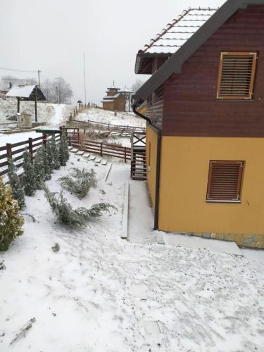 a house covered in snow next to a fence at VILA PLANINSKI SAN in Sekulić 