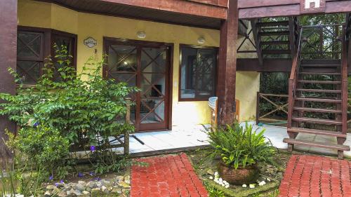 an open door of a house with a bench and plants at Casa Maresias Canto do mar - 50m da praia in Maresias