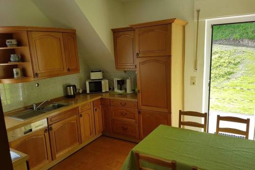 uma cozinha com armários de madeira, uma mesa e uma janela em Ferienhaus Urban mit Garage em Wimbach