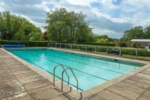 a large swimming pool with blue water at Signal Cottage at The Red House Estate in York