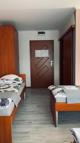 a room with three beds and a wooden door at Bianco - pokoje noclegowe in Częstochowa