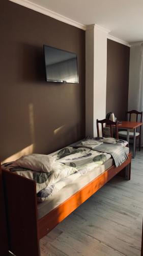 a bed in a room with a tv on the wall at Bianco - pokoje noclegowe in Częstochowa