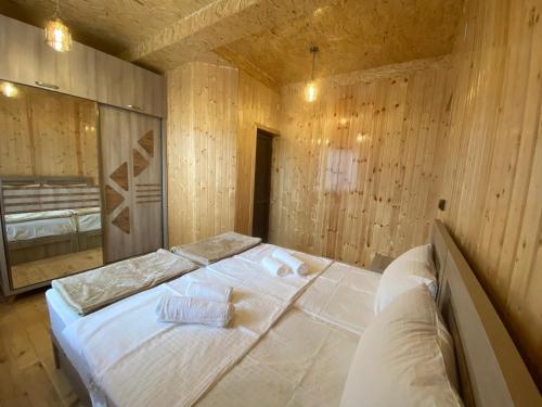 a large bed in a room with wooden walls at Guest House Sunrise in Khulo