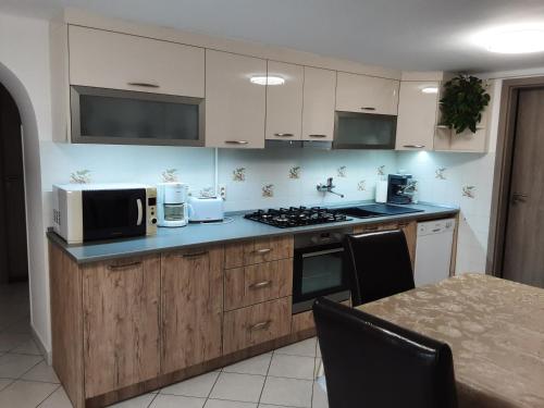 a kitchen with a stove and a microwave and a table at Tó apartman in Tihany