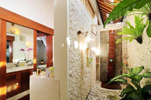 a bathroom with a stone wall at Villa Domus De Janas in Seminyak