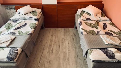 two beds in a room with wooden floors at Bianco - pokoje noclegowe in Częstochowa