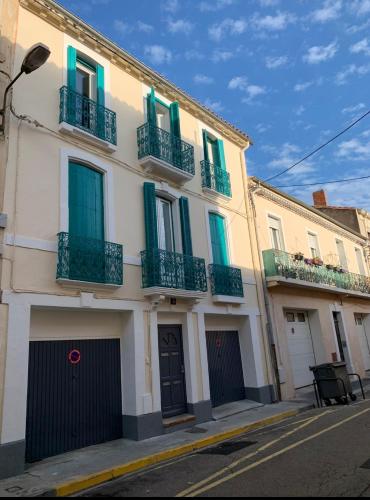a white building with green shutters on a street at Appartement Les Halles , Climatisation, Terrasse, Garage in Narbonne