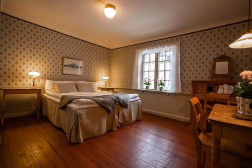 a bedroom with a bed and a table and a window at Hotell Dahlströmska gården in Vadstena