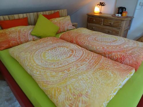ein Bett mit einer grünen und orangefarbenen Bettdecke darauf in der Unterkunft Wohlfühlhaus Immenstaad in Immenstaad am Bodensee