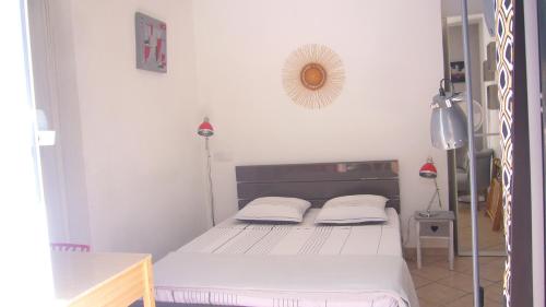 um pequeno quarto com uma cama com lençóis brancos em Les Chênes Verts em Valbonne