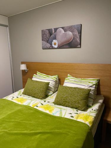 um quarto com uma cama com lençóis e almofadas verdes em Дом у спа-центра и озера em Imatra