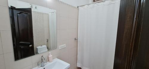 a white bathroom with a sink and a mirror at Nook Inn & Suites - MG ROAD METRO in Gurgaon