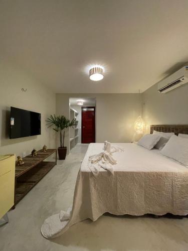 a bedroom with a large white bed and a flat screen tv at Ronco do Mar Cumbuco in Cumbuco