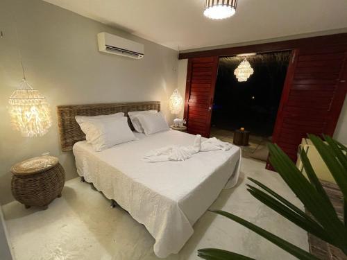 a bedroom with a bed with white sheets at Ronco do Mar Cumbuco in Cumbuco