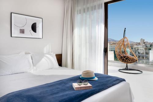 una habitación de hotel con una cama con sombrero y gafas de sol en Filopappou Hill Suites by Athens Stay, en Atenas