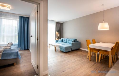 - un salon et une salle à manger avec un canapé bleu et une table dans l'établissement BEL MARE Apartament C202 PARKING GRATIS, à Międzyzdroje