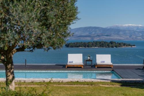 two chairs and a table next to a swimming pool at Villa BLUELINE in Alykes Potamou