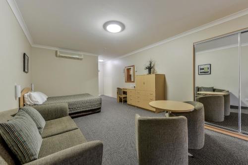 a living room with a couch and a bed at Golden Guitar Motor Inn in Tamworth
