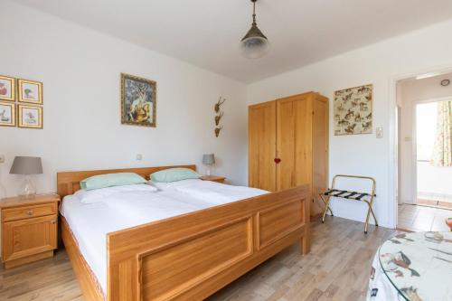 a bedroom with a large wooden bed with white sheets at Pension Tadtendrang in Tadten
