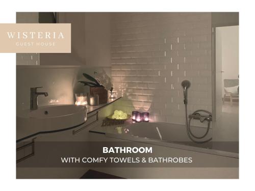 uma casa de banho com um lavatório e uma banheira com velas em Wisteria Guest House em Villers-lʼÉvêque