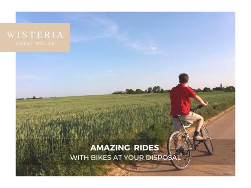 a man riding a bike down a road next to a field at Wisteria Guest House in Villers-lʼÉvêque