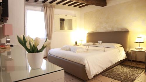 1 dormitorio con 1 cama y un jarrón de flores en ComeCasaTua - il Vicoletto, en Verona