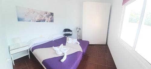 Habitación pequeña con cama con sábanas moradas y blancas. en Las Toscas, en La Frontera