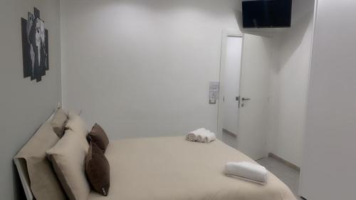 a white room with a bed with pillows and a television at One Hundred Rooms in Rome