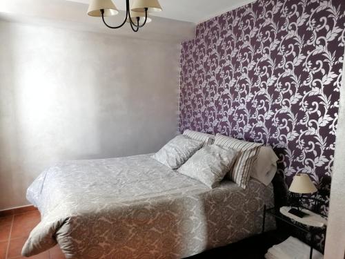 a bedroom with a bed and a purple wall at La Roca de Setenil in Setenil