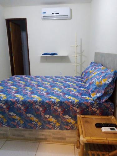 a bed with a blue comforter and a table at Pousada Portuguesa in Natal