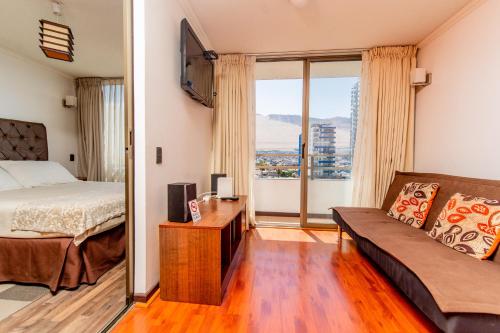 1 dormitorio con cama, sofá y ventana en Departamentos Alpro Cavancha, en Iquique