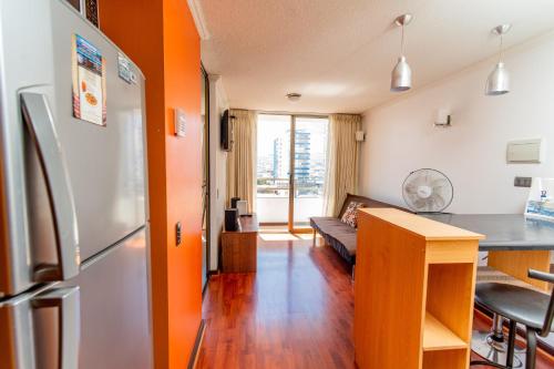 a kitchen and living room with an orange wall at Departamentos Alpro Cavancha in Iquique