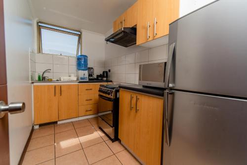 a kitchen with a stainless steel refrigerator and wooden cabinets at Departamentos Alpro Cavancha in Iquique