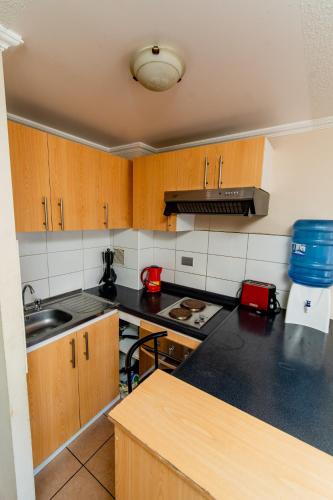 a kitchen with wooden cabinets and a black counter top at Departamentos Alpro Cavancha in Iquique