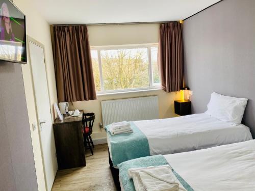 a hotel room with two beds and a window at Almond Tree Hotel in Bicester