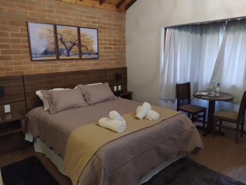 a bedroom with a bed with towels on it at Pousada Alto dos Pinheiros in Monte Verde