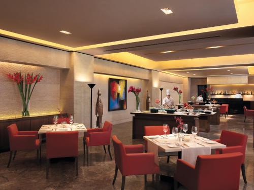 a restaurant with tables and chairs and a chef in the kitchen at The Oberoi Mumbai in Mumbai