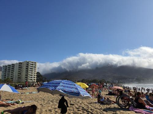 a group of people on a beach with umbrellas at Departamento Lago & Mar in Papudo