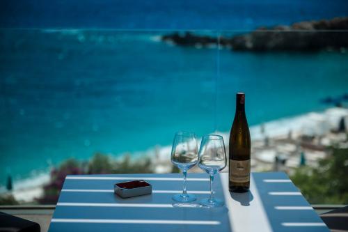 a bottle of wine and two wine glasses on a table at Folie Marine Hotel & Beach Club in Jal
