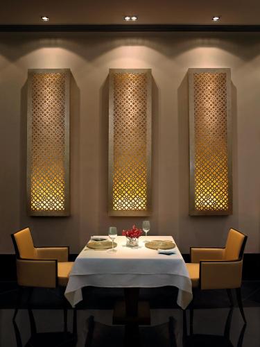 a dining room with a table and three windows at The Oberoi Mumbai in Mumbai